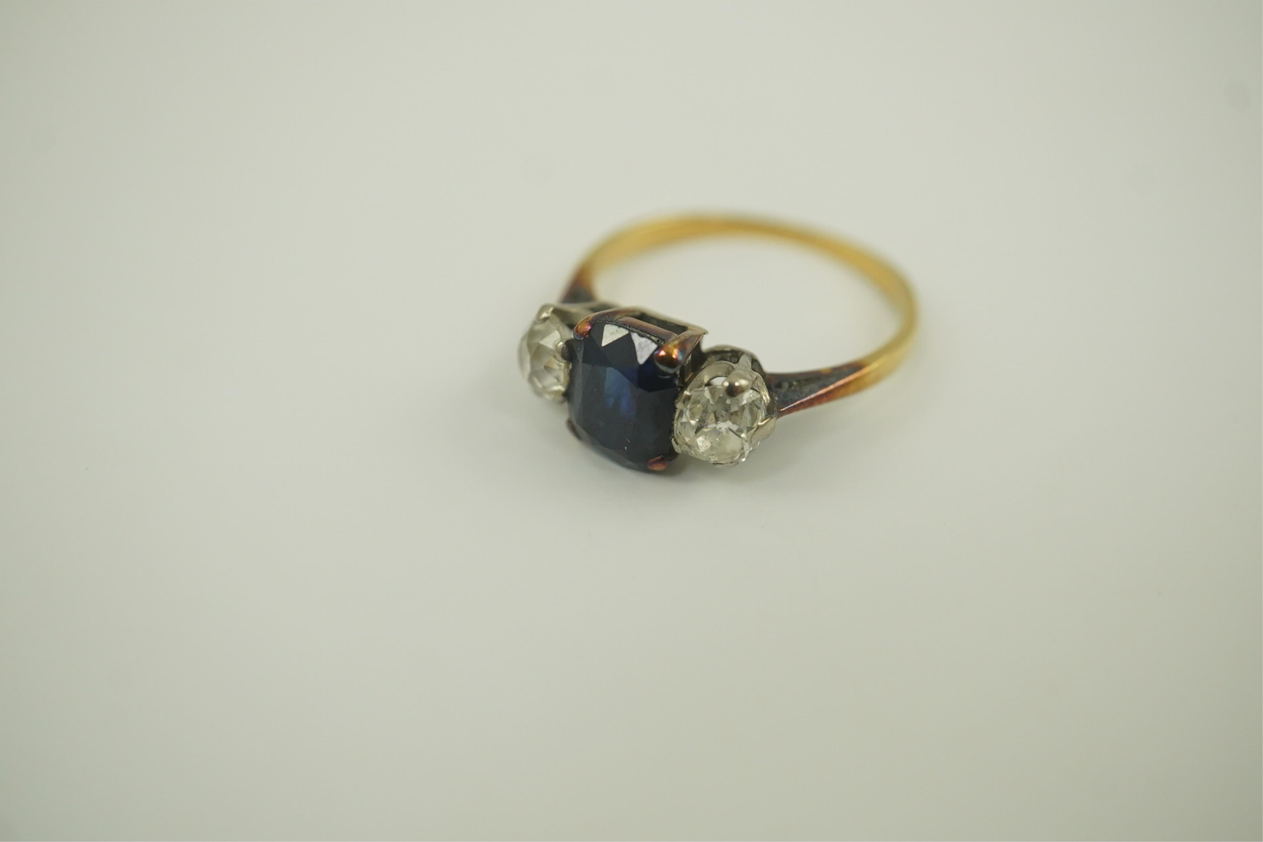 A gold, single stone oval sapphire and two stone round cut diamond set ring